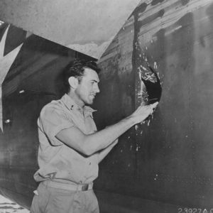 Louis Zamperini looks at hole in aircraft